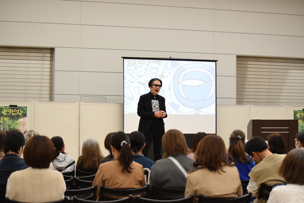 絵画の作品を投影して講演を行う国広富之さん。