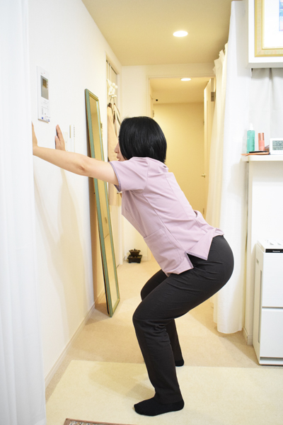 壁に手をつくことで、腰周りや骨盤底筋群に効かせやすくなる。